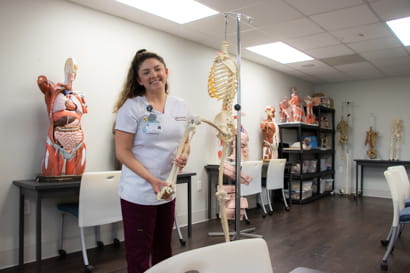 Female student in a classroom handling a model