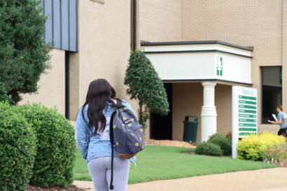 Woman holding a backpack and walking towards a building