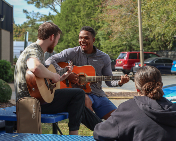 Two male students playing guitar outside