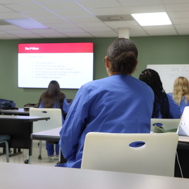 Female student in a classroom looking at a projector