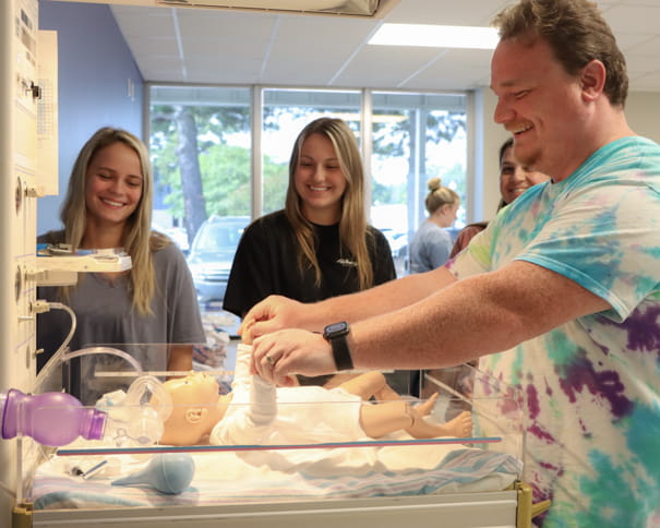 Group of nursing students practicing with a newborn manikin