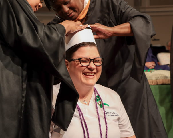Female nursing graduate smiling and being capped at graduation