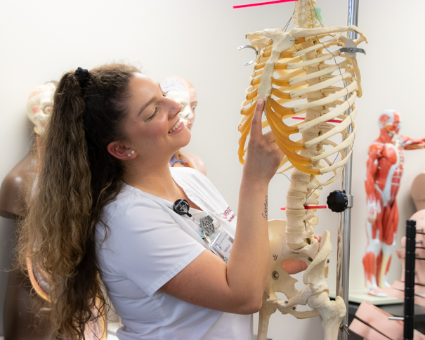 Female student using a skeletal model
