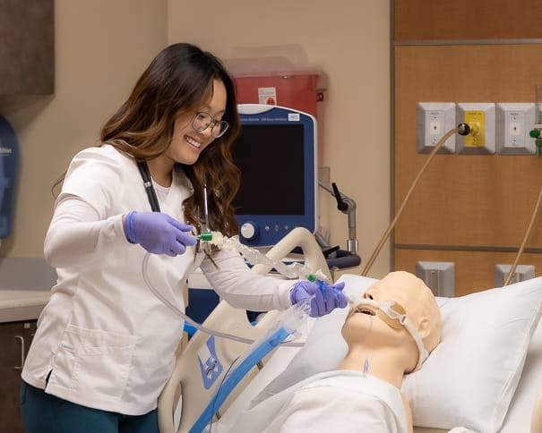 Student practicing trachea care with a mannequin.