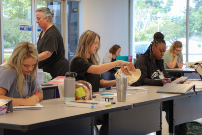 Female Student sitting in classroom handling an anatomical model.