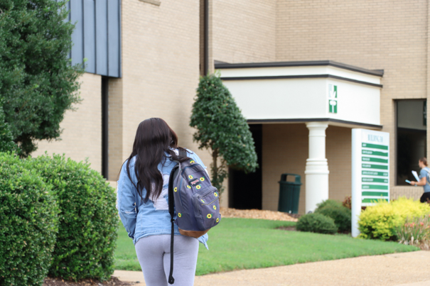 Female student walking towards the library building.