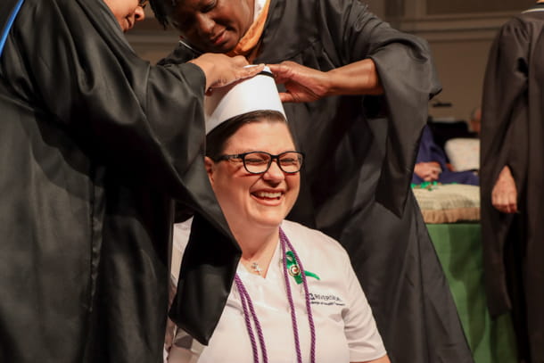 Women having a nursing hat pinned to her head and smiling.