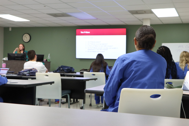 Women sitting in a classroom facing a projector screen.